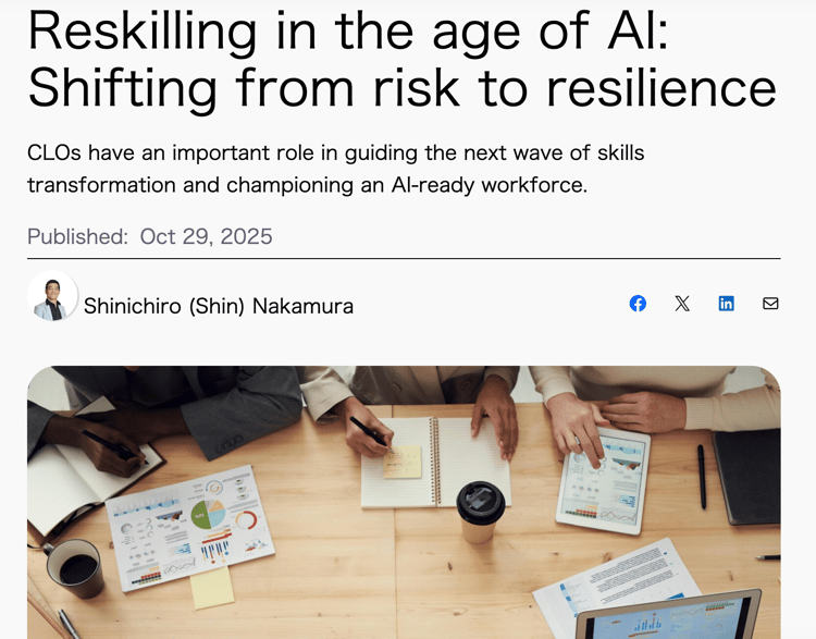 A high-angle, close-up shot of a diverse business team collaborating around a wooden conference table. The focus is on their hands and the various documents spread across the table, including colorful charts, graphs, and paper documents. Team members are seen writing in notebooks, holding pens, and interacting with a tablet and a laptop screen (showing charts), suggesting a strategic planning or data analysis meeting. The image illustrates the theme of the adjacent article, focusing on the cognitive work involved in reskilling and workforce transformation in the age of AI.